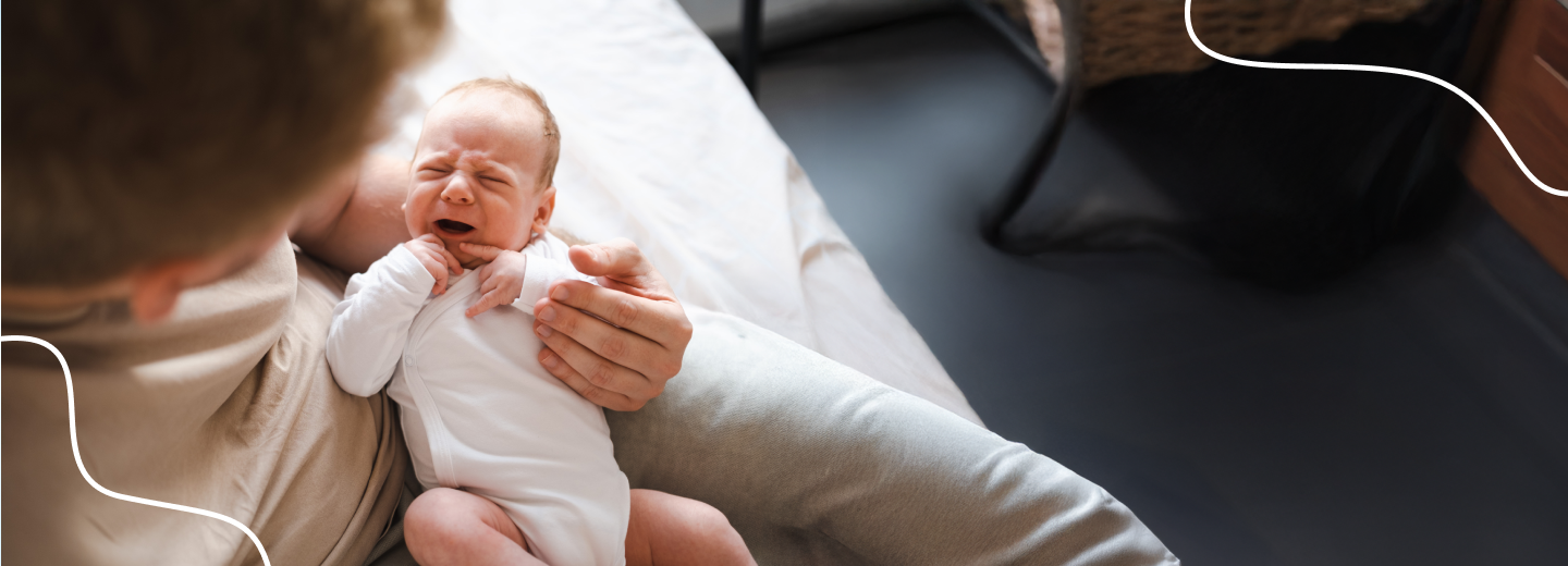 Wenende zuigeling op de schoot van vader